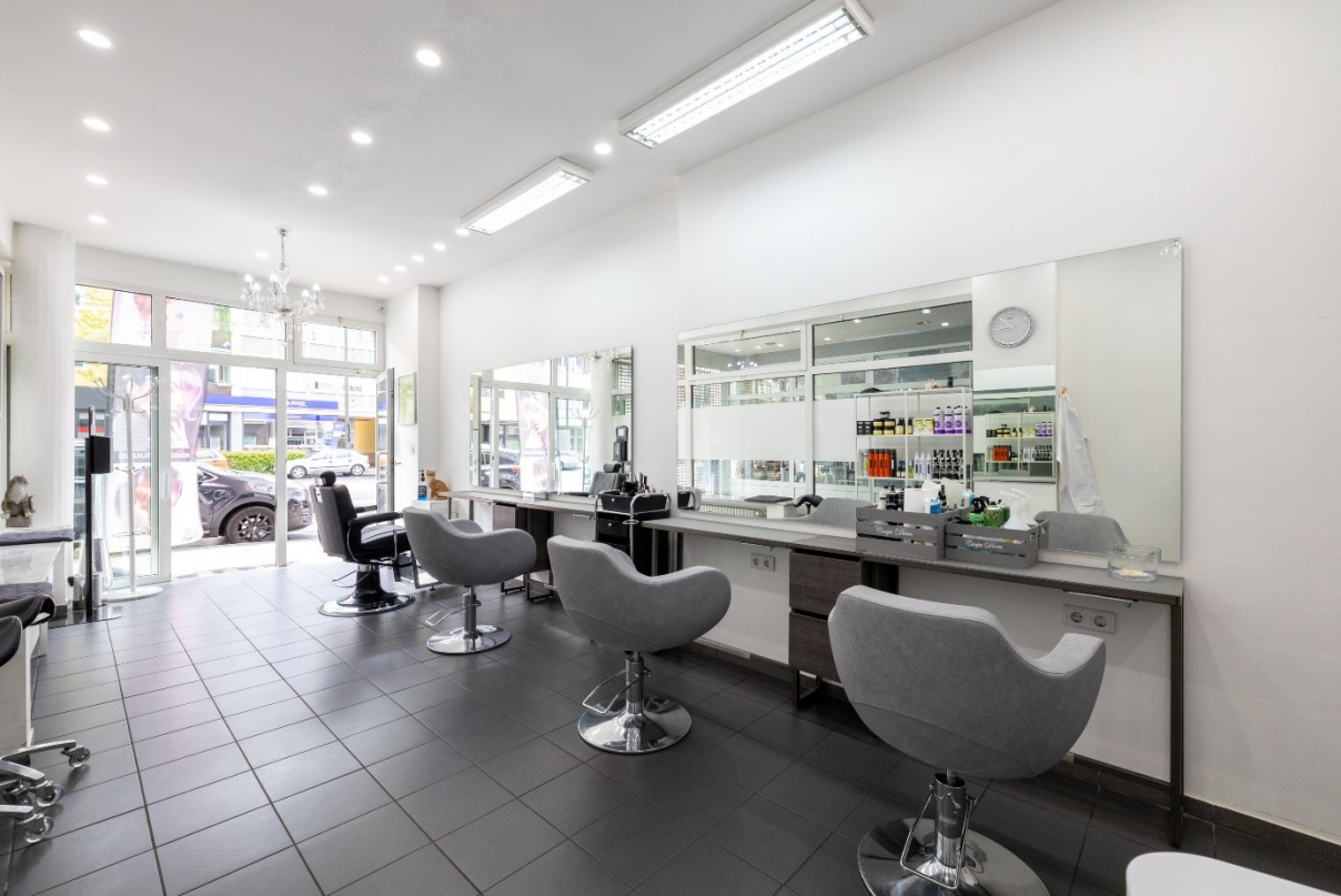 Seitlicher Blick auf die Friseursitze mit zwei Spiegeln – moderne Doppelarbeitsplätze mit großzügigen, freistehenden Spiegeln, die optimale Sicht von beiden Seiten ermöglichen und durch stilvolles Design den Salonraum elegant strukturieren